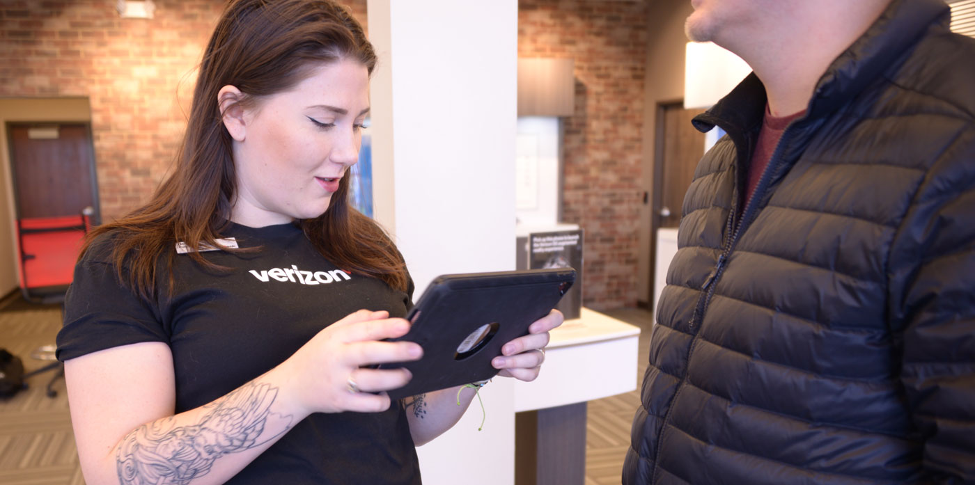 A young female BeMobile employee helping a male customer with his tablet
